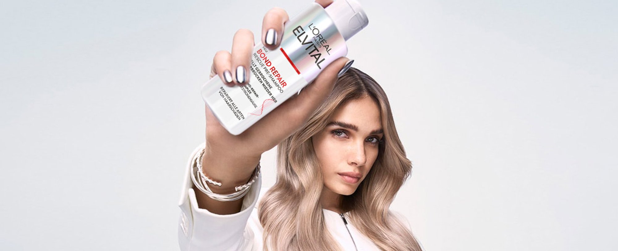 Frau hält Elvital Bond Repair Rescue Pre-Shampoo in der Hand
