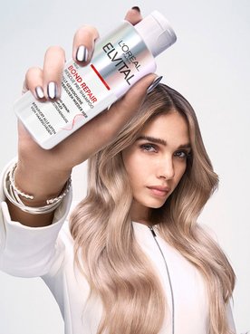 Frau hält Elvital Bond Repair Rescue Pre-Shampoo in der Hand
