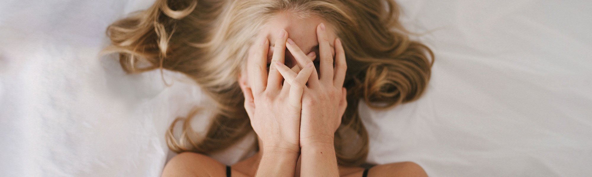 Frau mit aschblondem Haar liegt im Bett