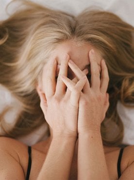 Frau mit aschblondem Haar liegt im Bett