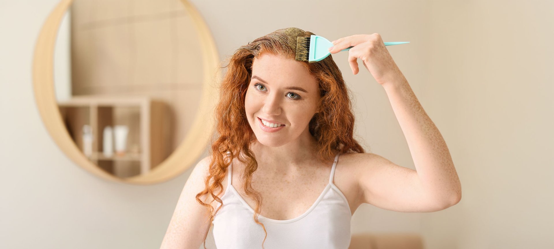 Eine junge Frau trägt eine rotbraune Coloration auf ihre gewellten langen Haare auf.