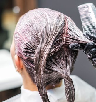Kopf einer Frau von hinten betrachtet auf dem eine Coloration aufgetragen wird