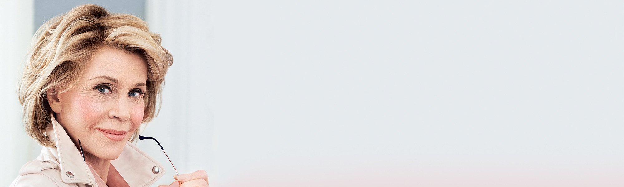 Jane Fonda hat eine Brille mit rosa Brillengläsern in Herzform in der Hand