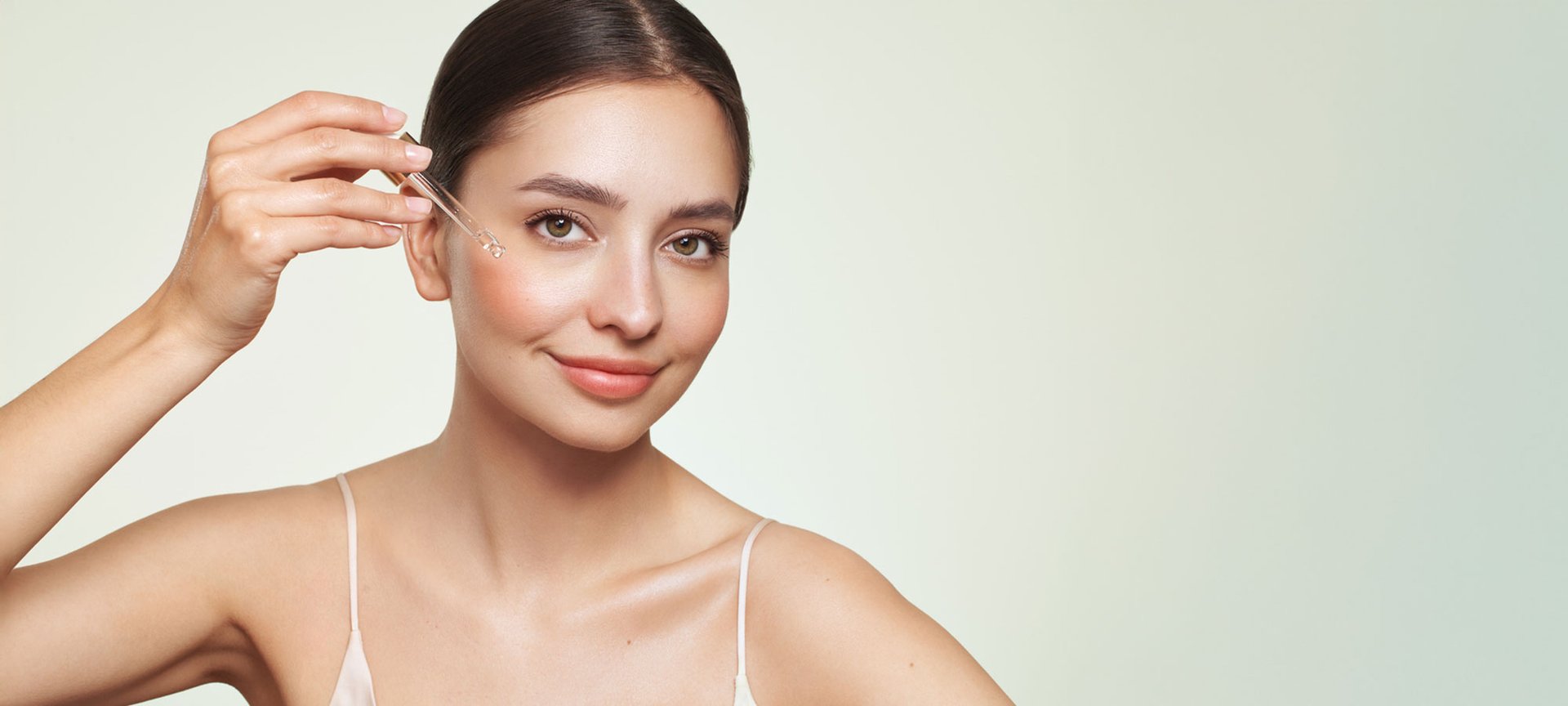 Eine Frau trägt sich mit einer Pipette Retinol auf ihr Gesicht.