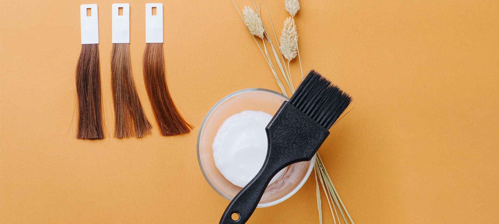 Verschiedene Haarfarbproben eine Tönung mit Bürste und Zierblumen vor gelben Hintergrund.