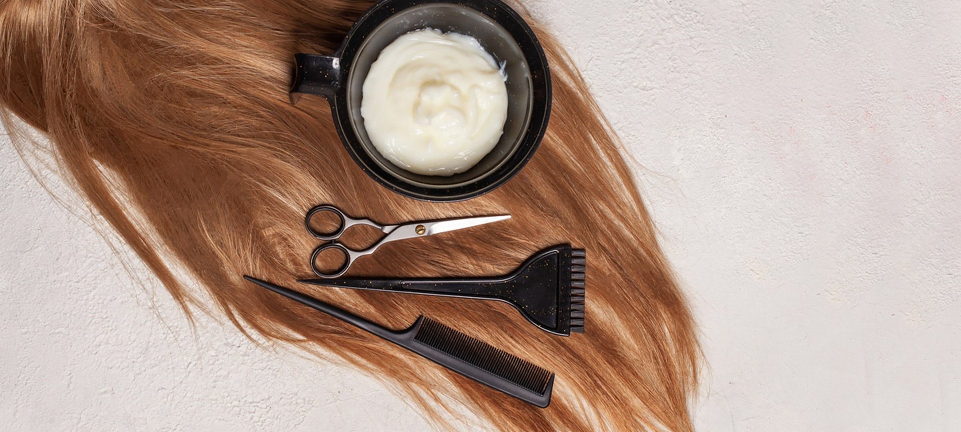 Tönung, Schere, Bürste und Kamm auf braunem Haarschopf