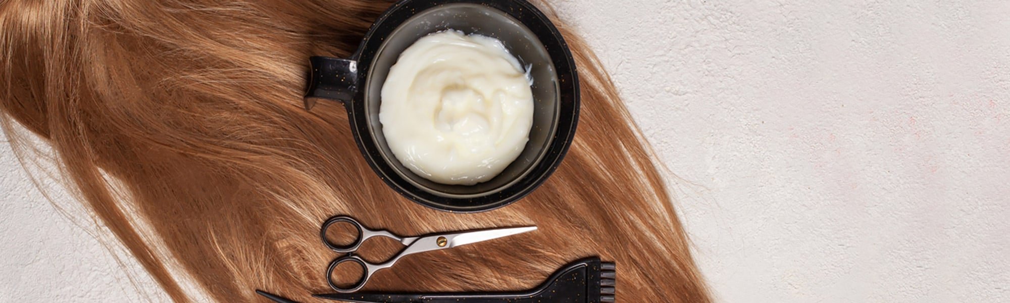 Tönung, Schere, Bürste und Kamm auf braunem Haarschopf
