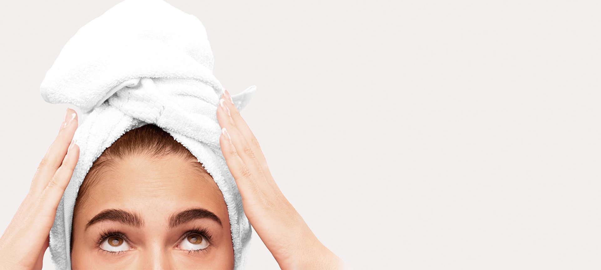 Frau trägt nach der Haarwäsche ein Handtuch um den Kopf