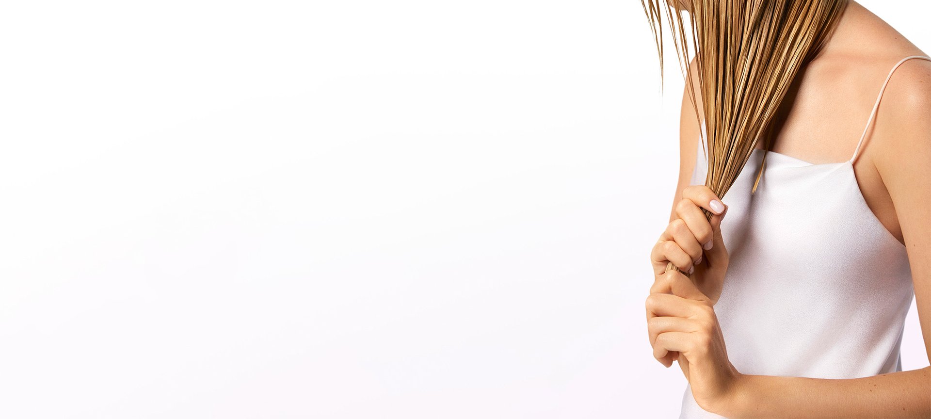 Eine junge Frau umfasst ihre langen dunkelblonden Haare