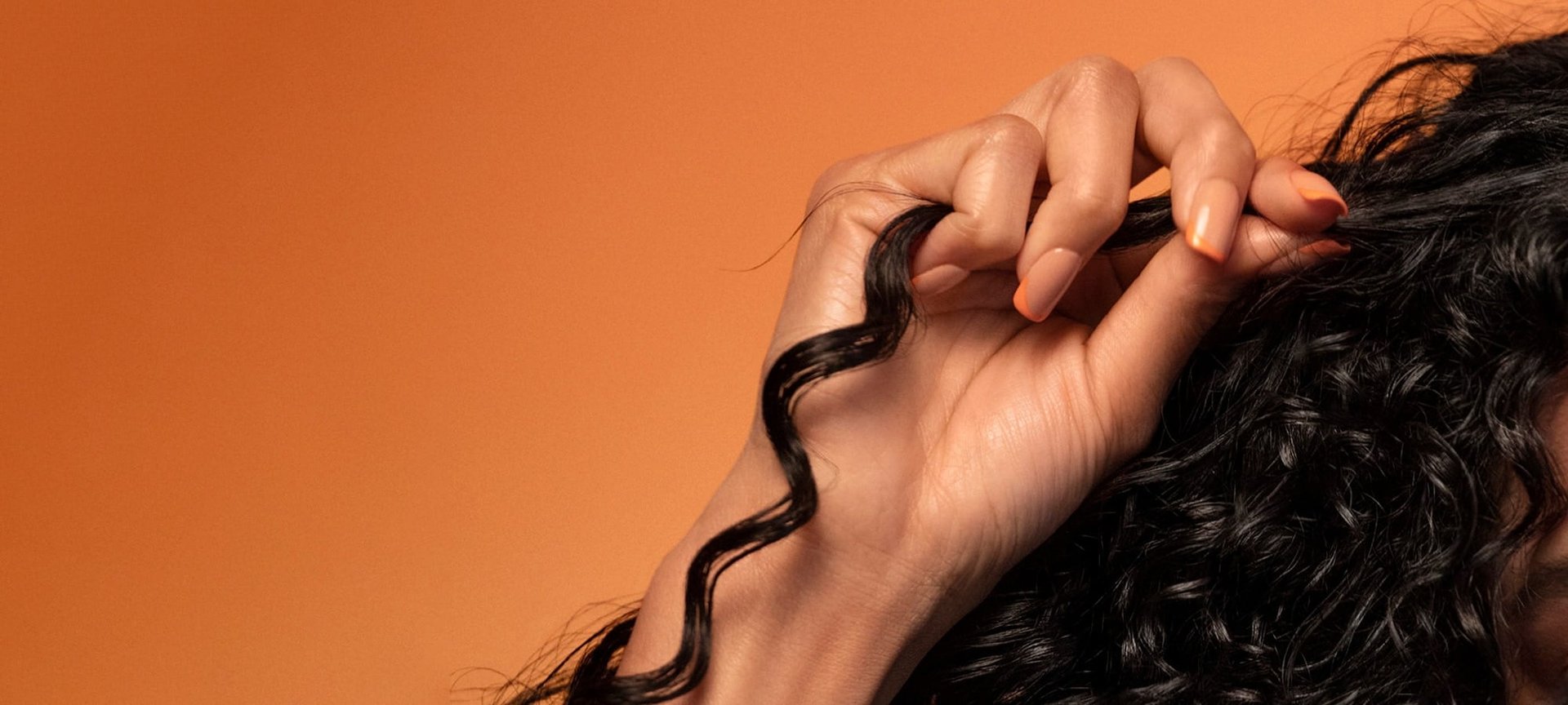 Eine Frau umfasst eine Locke ihrer langen gelockten Haare