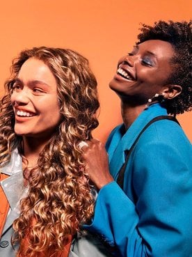 Drei junge Frauen mit schwarzen & blonden lockigen Haaren