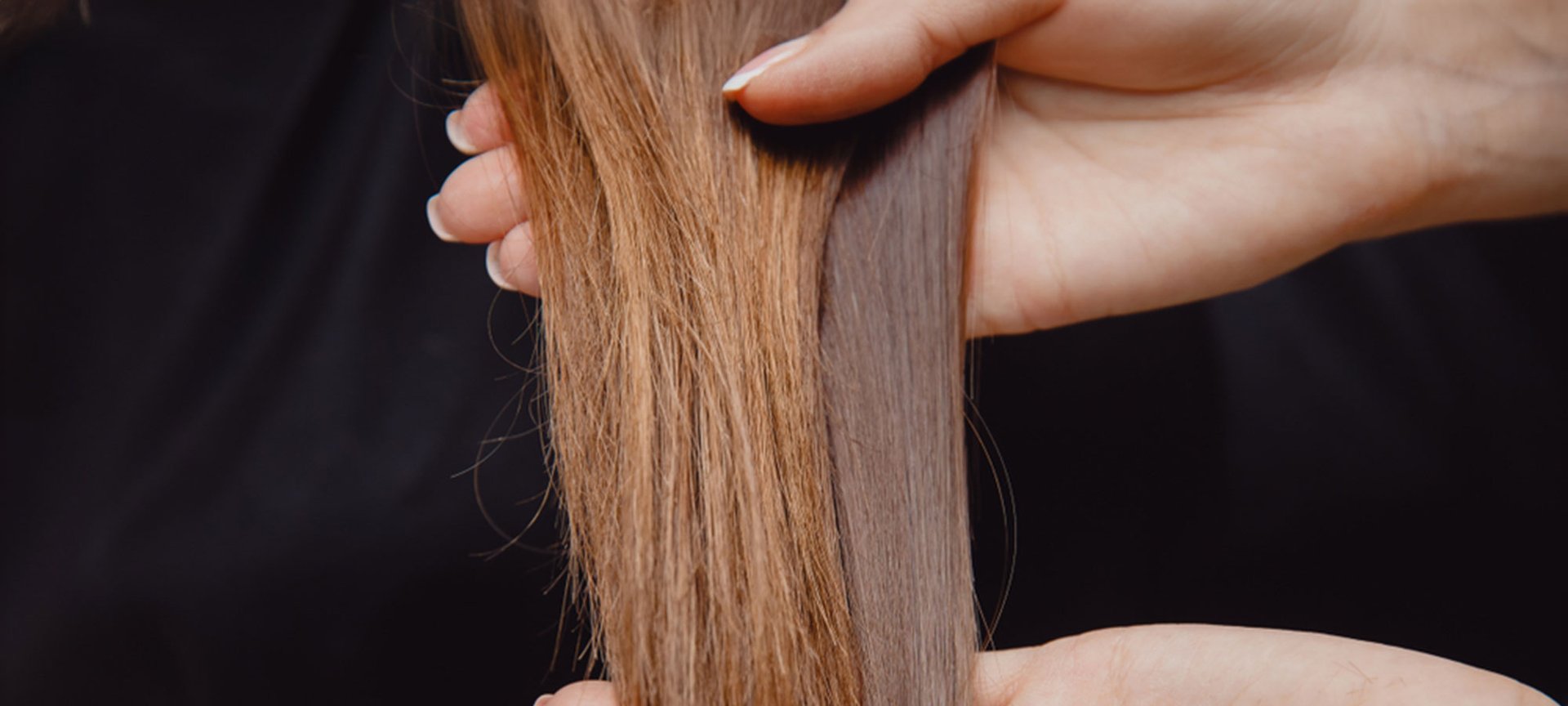 Langes braunes Haar wird von zwei Händen gehalten