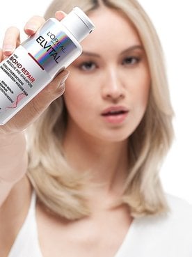 Eine Frau hält ein Elvital Bond repair in ihrer Hand