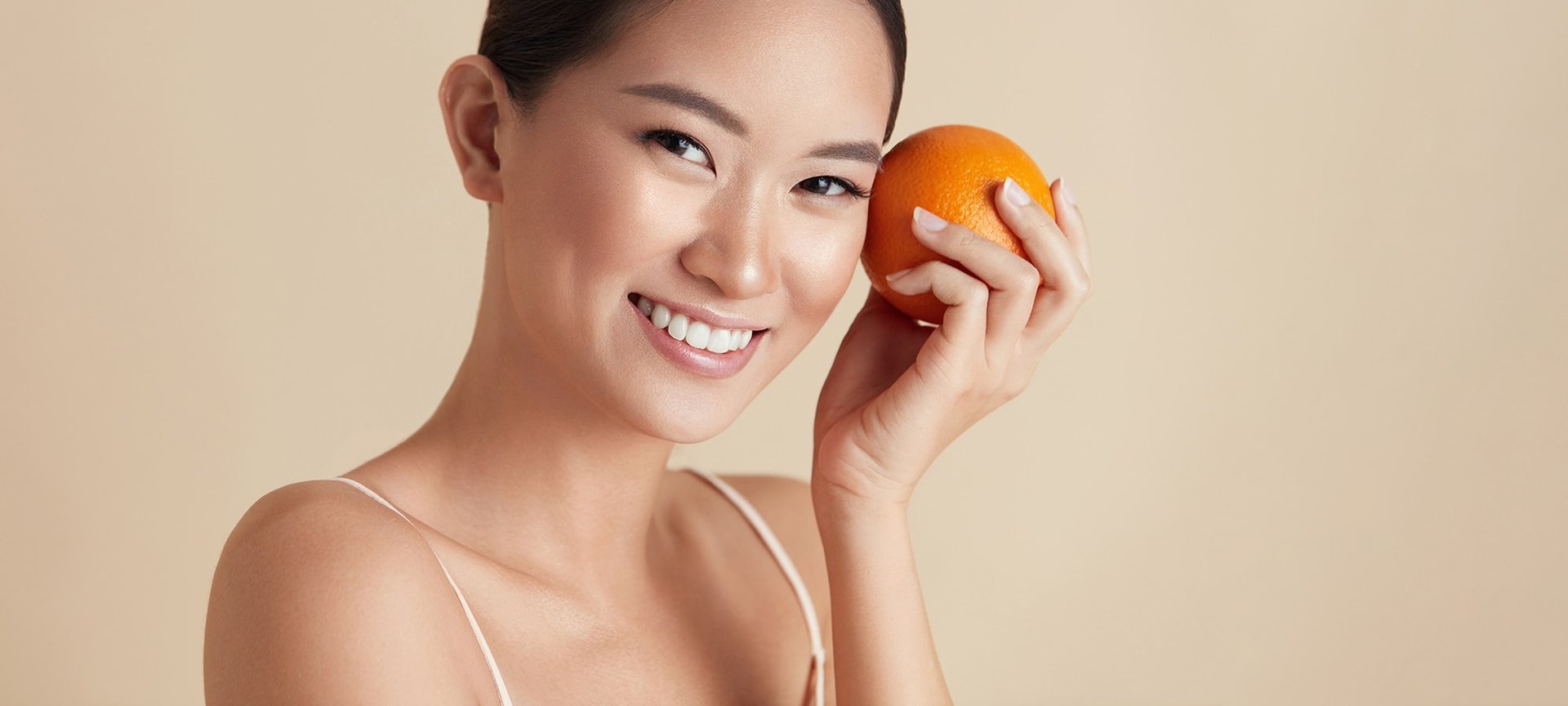 Eine Junge Frau hält sich eine Orange in der Hand