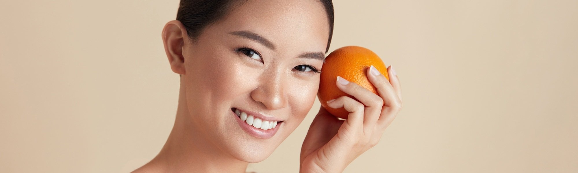 Eine Junge Frau hält sich eine Orange in der Hand