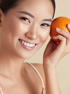 Eine Junge Frau hält sich eine Orange in der Hand
