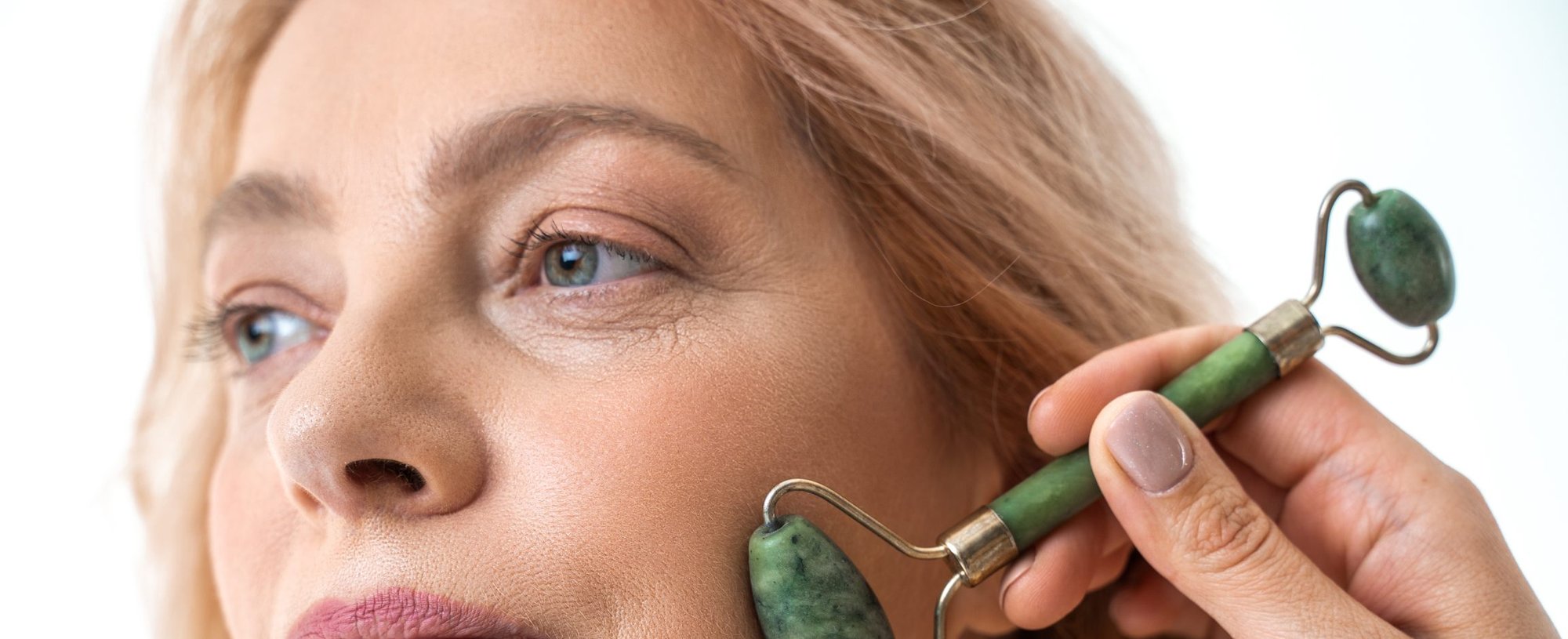 Frau massiert ihr Gesicht mit einem grünen Jade-Roller.