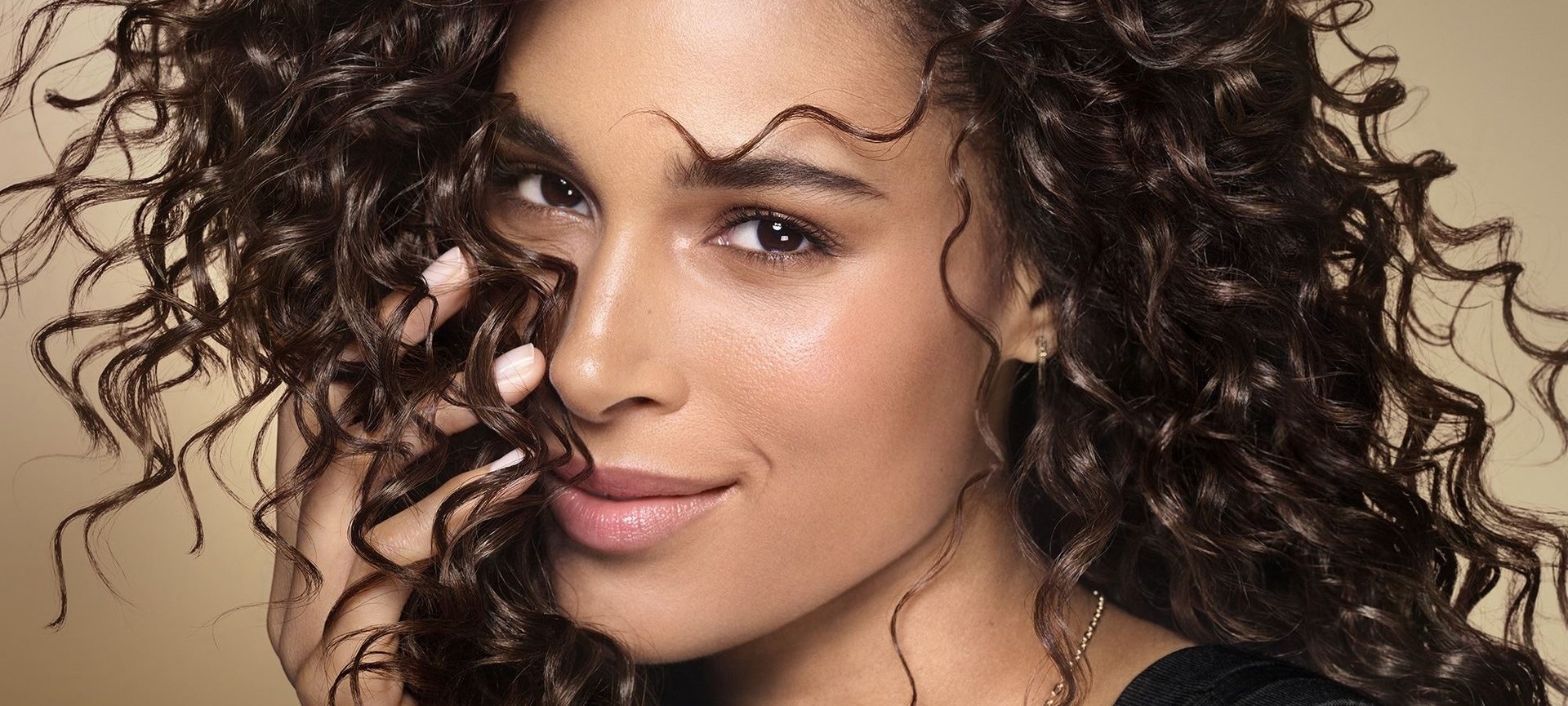 Banner mit Cindy Bruna, die ihr voluminöses, lockiges Haar trägt.