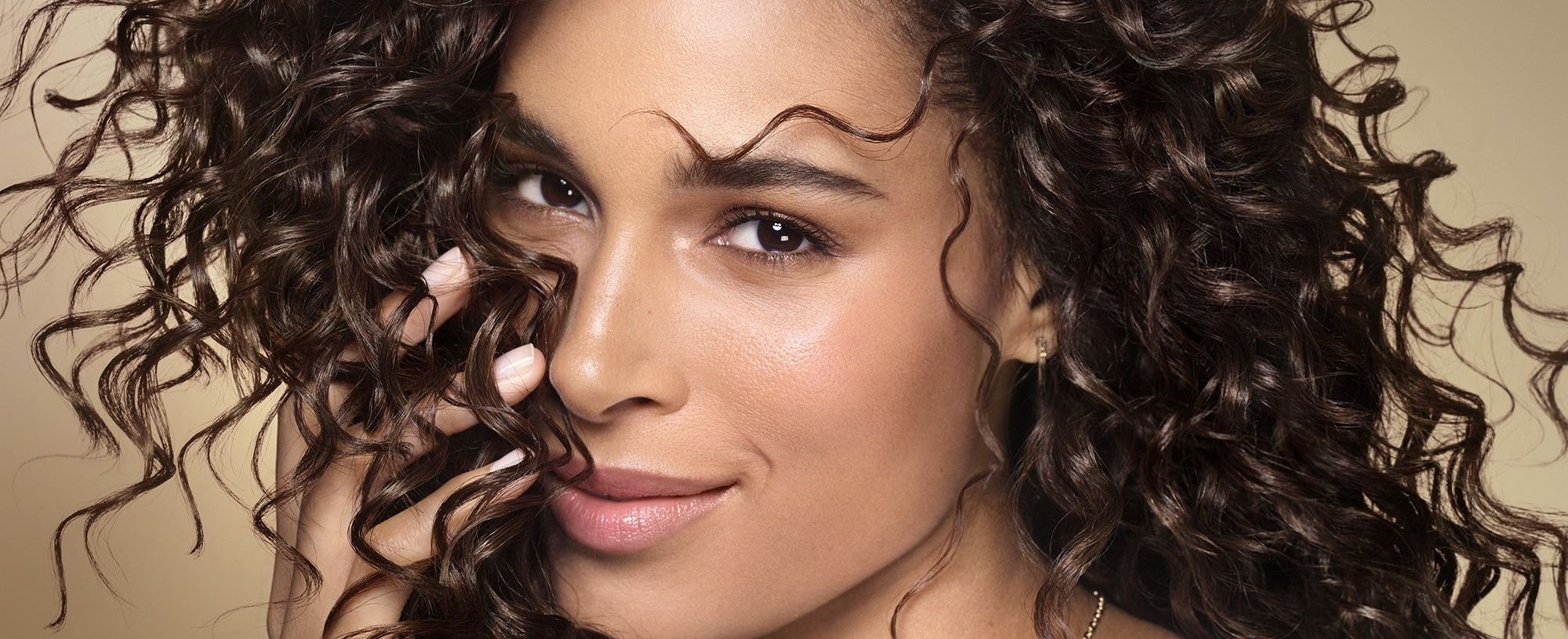 Banner mit Cindy Bruna, die ihr voluminöses, lockiges Haar trägt.
