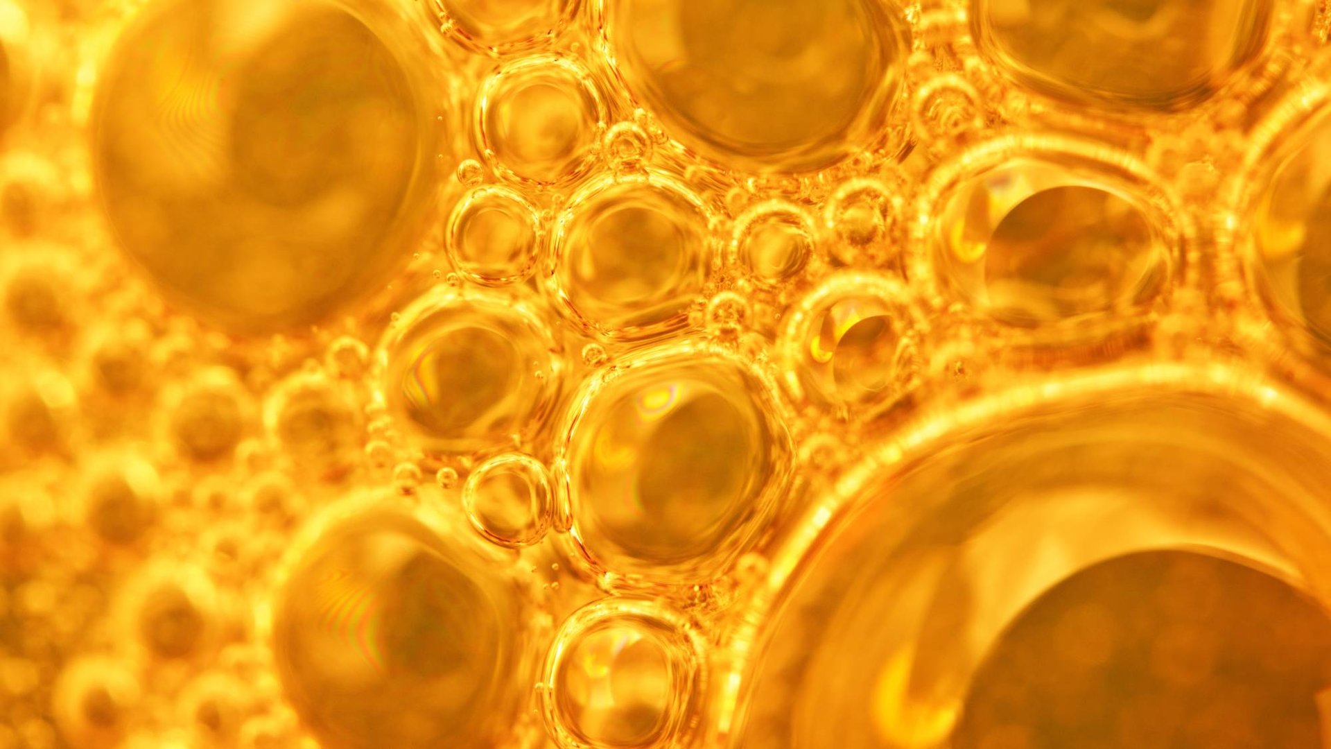 Goldene Bläschen in Flüssigkeit, Symbolbild für Kollagen-Peptide in Hautpflege.