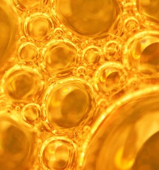 Goldene Bläschen in Flüssigkeit, Symbolbild für Kollagen-Peptide in Hautpflege.