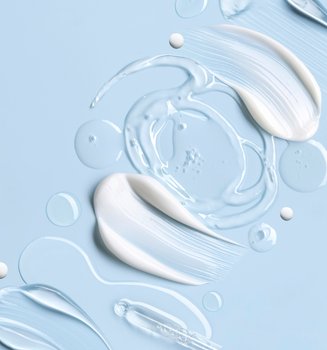 Weiße Creme, transparentes Gel und Tropfen als Texturen auf hellblauem Hintergrund