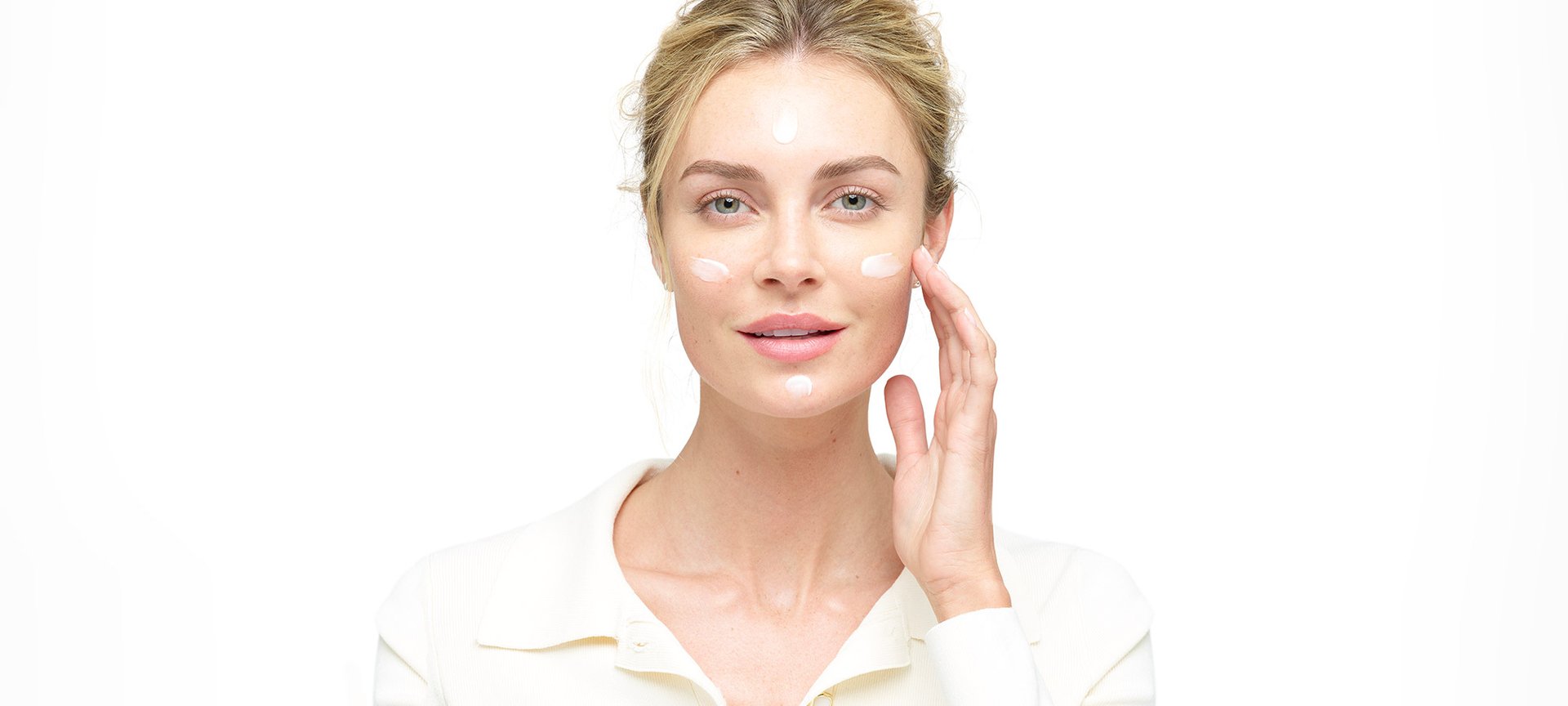 Eine junge Frau trägt eine Creme auf ihre Wangen auf