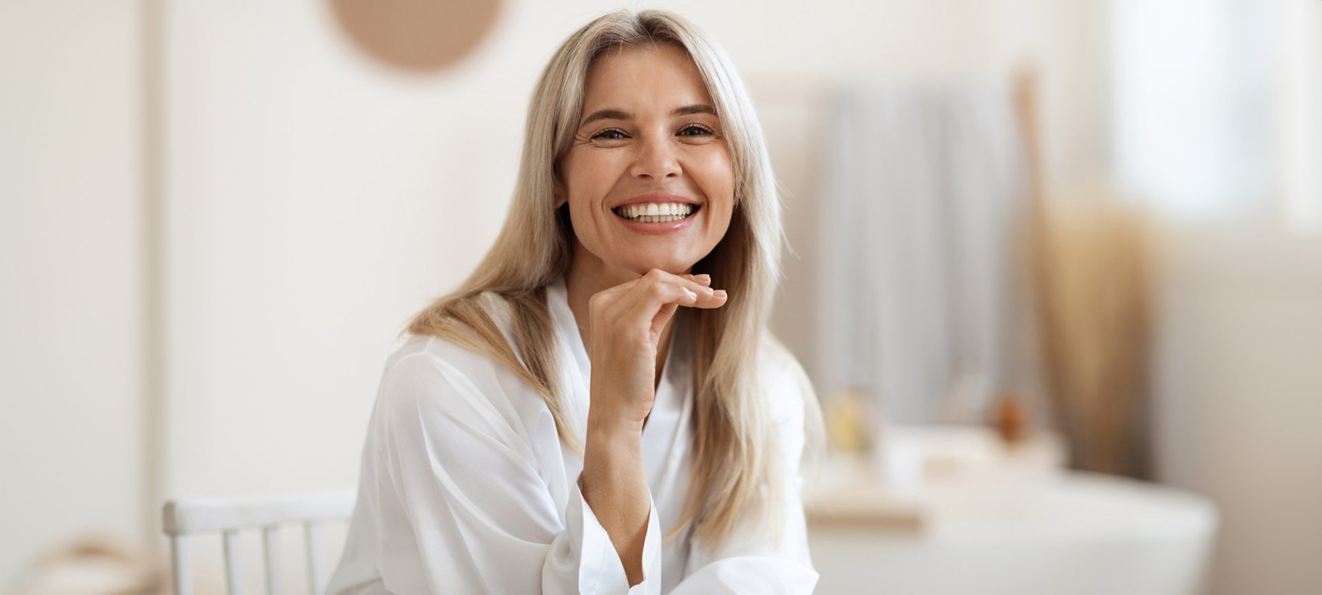 Eine lächelnde junge Frau im Bademantel mit langen blonden Haaren