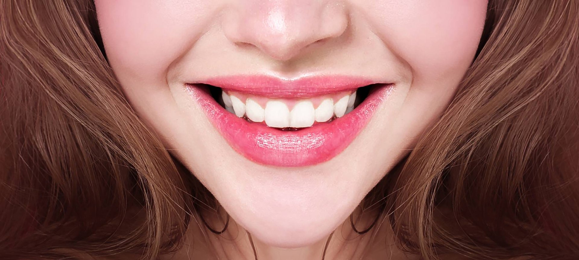 Nahaufnahme vom lächelnden Mund einer jungen Frau mit Lip Tint und weißen  Zähnen