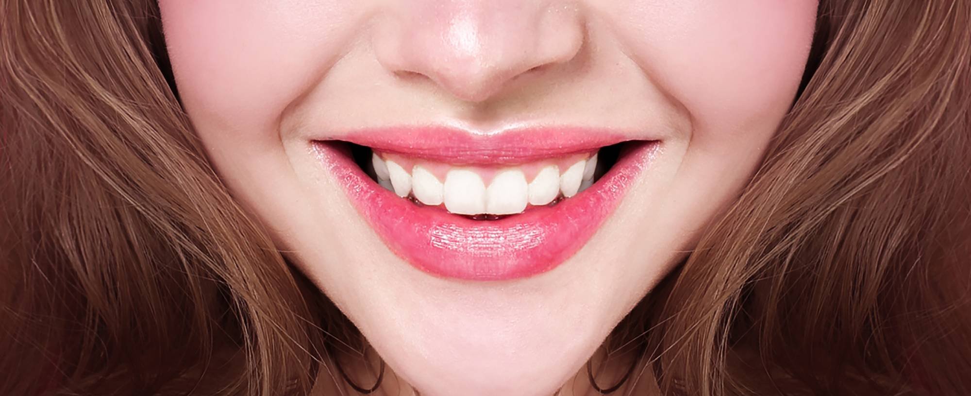 Nahaufnahme vom lächelnden Mund einer jungen Frau mit Lip Tint und weißen Zähnen