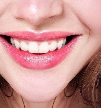 Nahaufnahme vom lächelnden Mund einer jungen Frau mit Lip Tint und weißen Zähnen