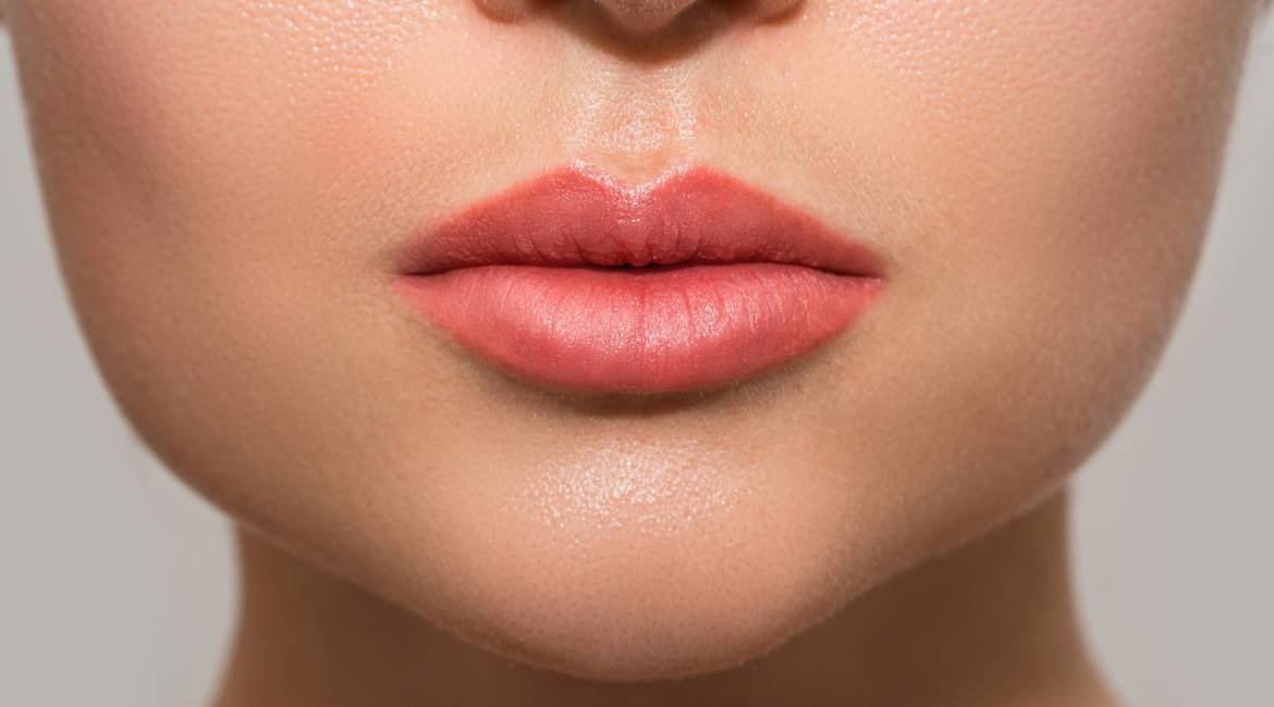 Nahaufnahme der unteren Gesichtshälfte einer jungen Frau mit plumpen Lippen  und rosa Lip Tint
