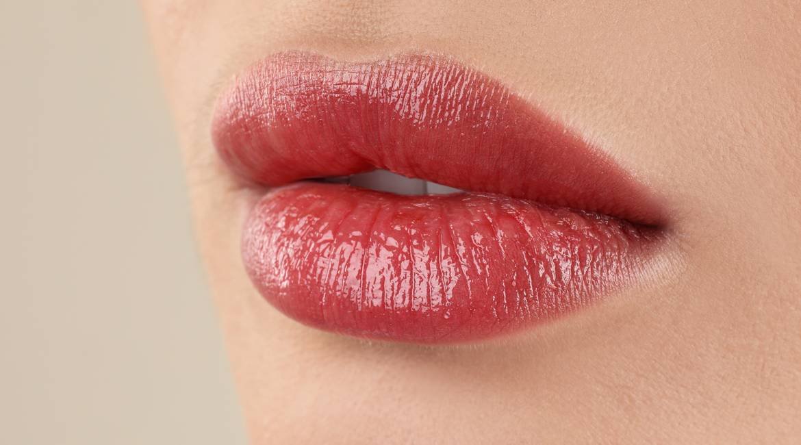 Nahaufnahme vom leicht geöffneten Mund einer jungen Frau mit rosa-rotem Lip  Tint