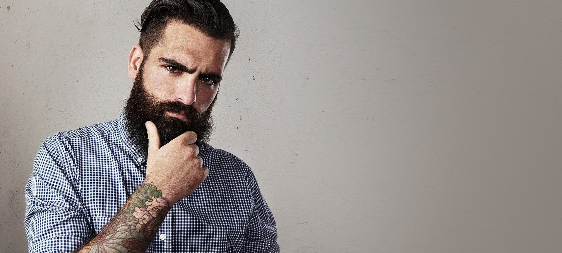 Dunkelhaariger Mann mit langem Hipster-Bart schaut nachdenklich