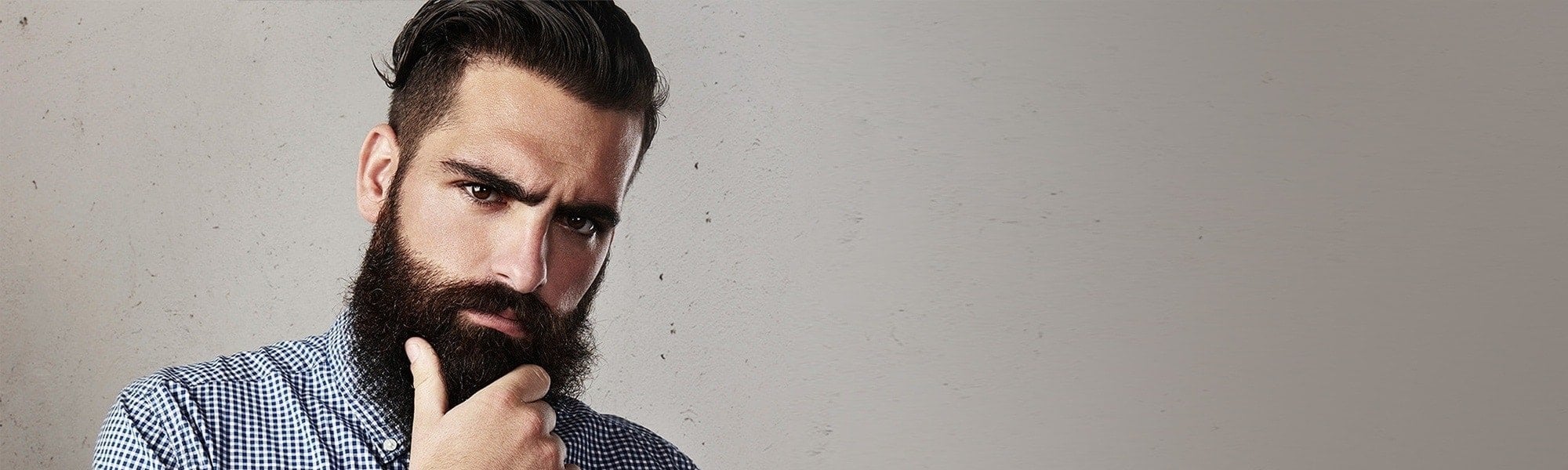 Dunkelhaariger Mann mit langem Hipster-Bart schaut nachdenklich