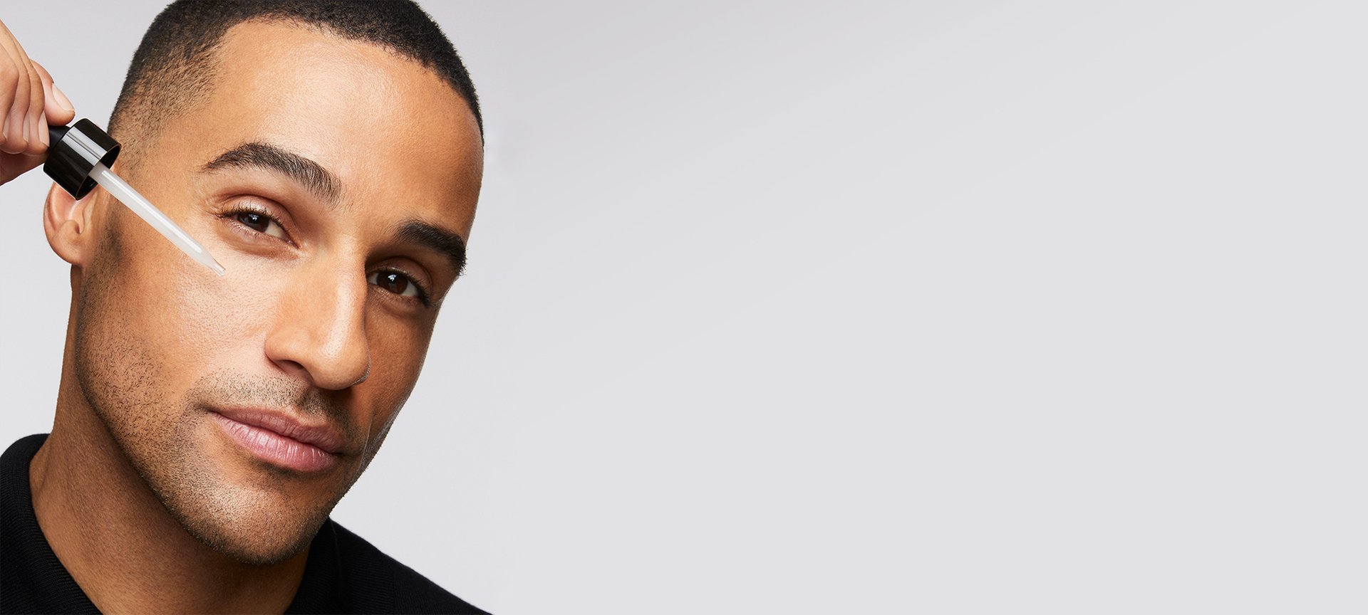 Ein Mann trägt mit einer Pipette ein Serum auf seine Wange auf