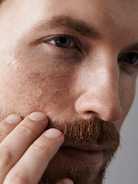 Ein Mann betrachtet sein Gesicht im SPiegel