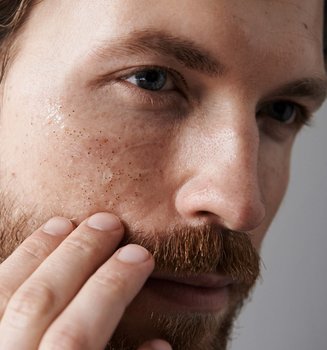 Ein Mann betrachtet sein Gesicht im SPiegel
