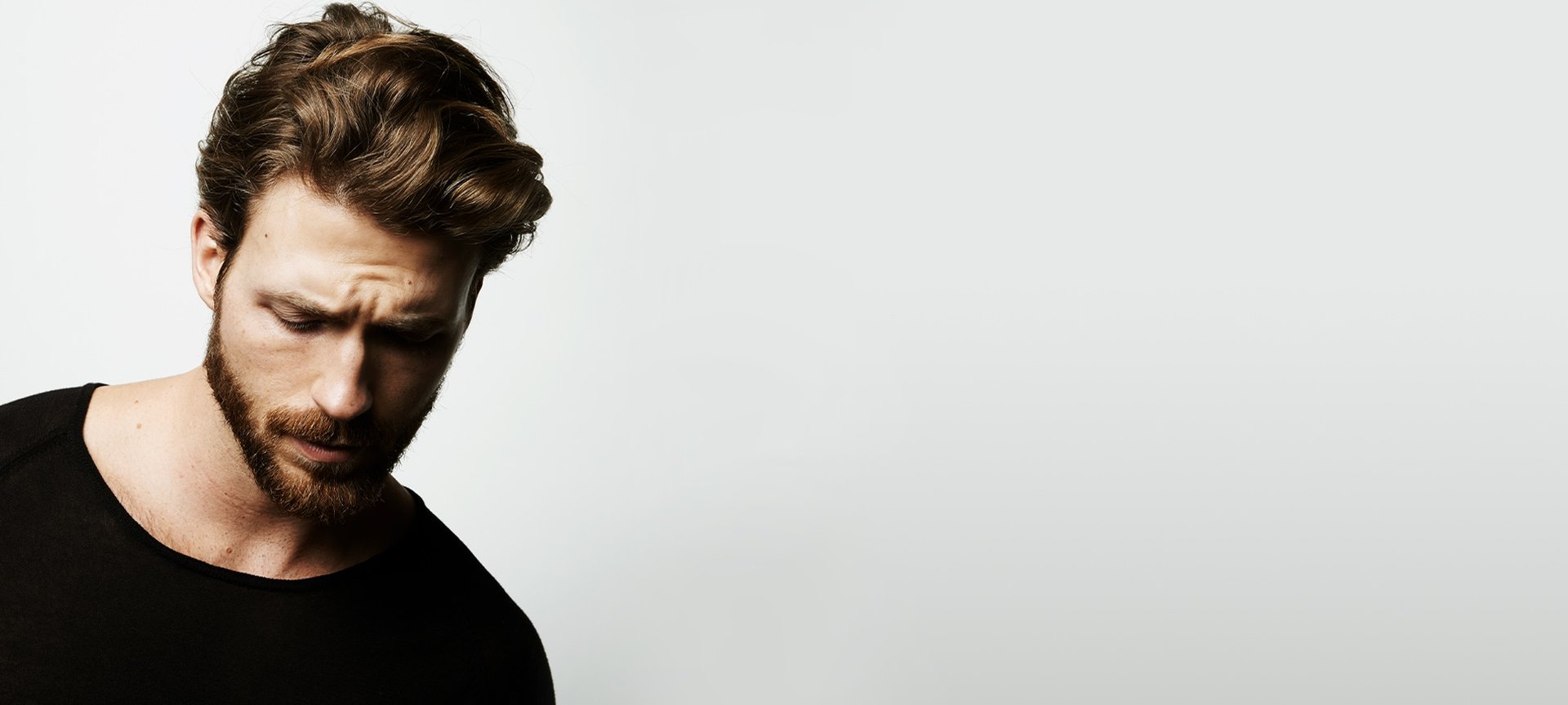 Mann mit gepflegten Haaren blickt nach unten