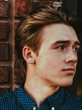 Mann mit blonden mittellangen Haaren, schaut zur Seite.