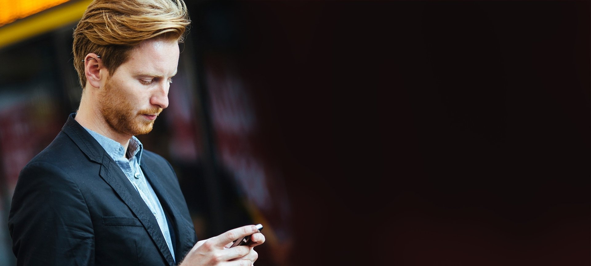 Rothaariger Mann schaut auf sein Smartphone