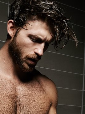 Mann mit Surferfrisur unter der Dusche