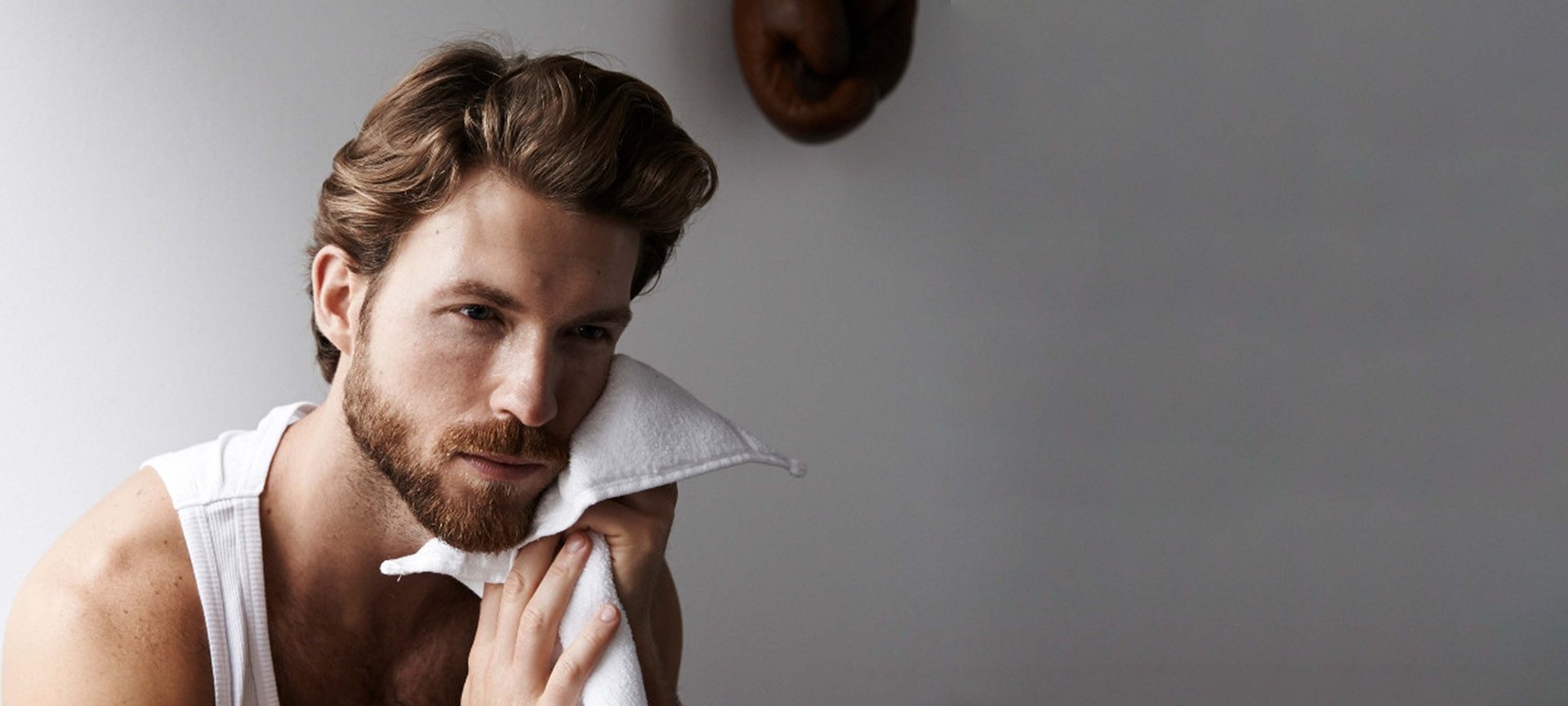 Mann trocknet sein gepflegtes Gesicht mit einem Handtuch ab.