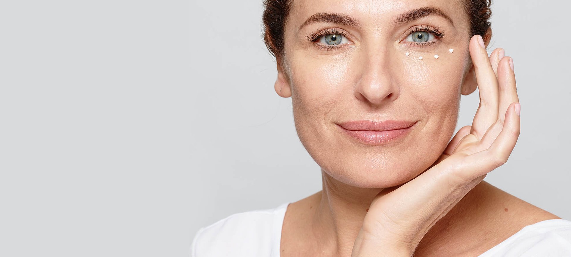 Eine Frau pflegt ihre Augen mit einer Creme