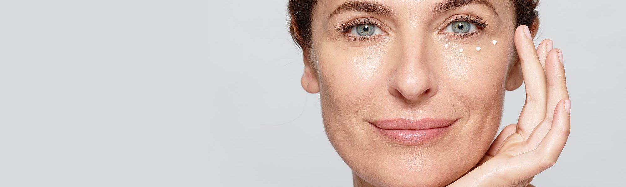 Eine Frau pflegt ihre Augen mit einer Creme