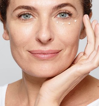 Eine Frau pflegt ihre Augen mit einer Creme