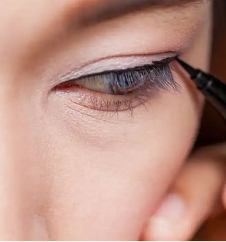 Frau trägt Eyeliner auf und schaut nach unten