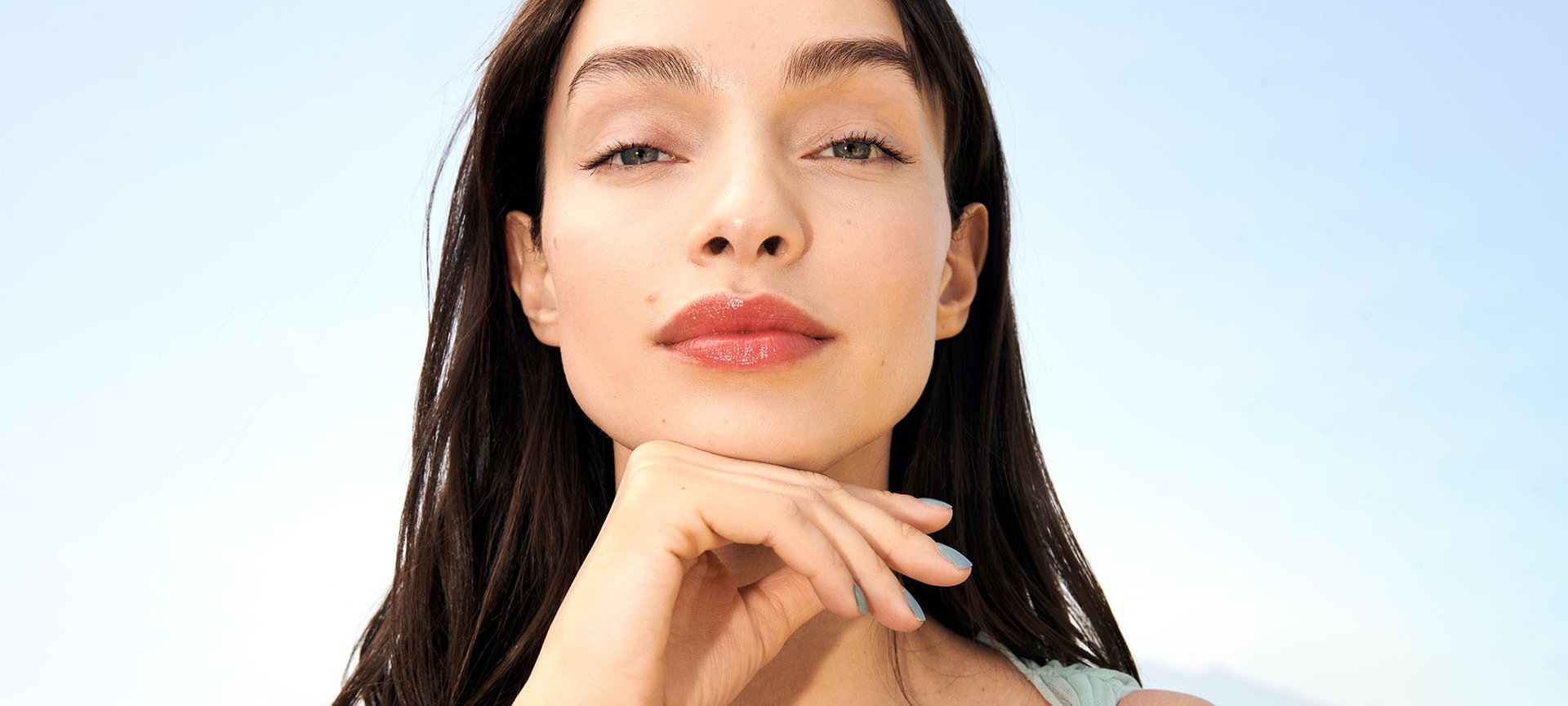 Eine junge Frau mit langen dunklen Haaren und Lipgloss auf ihren Lippen