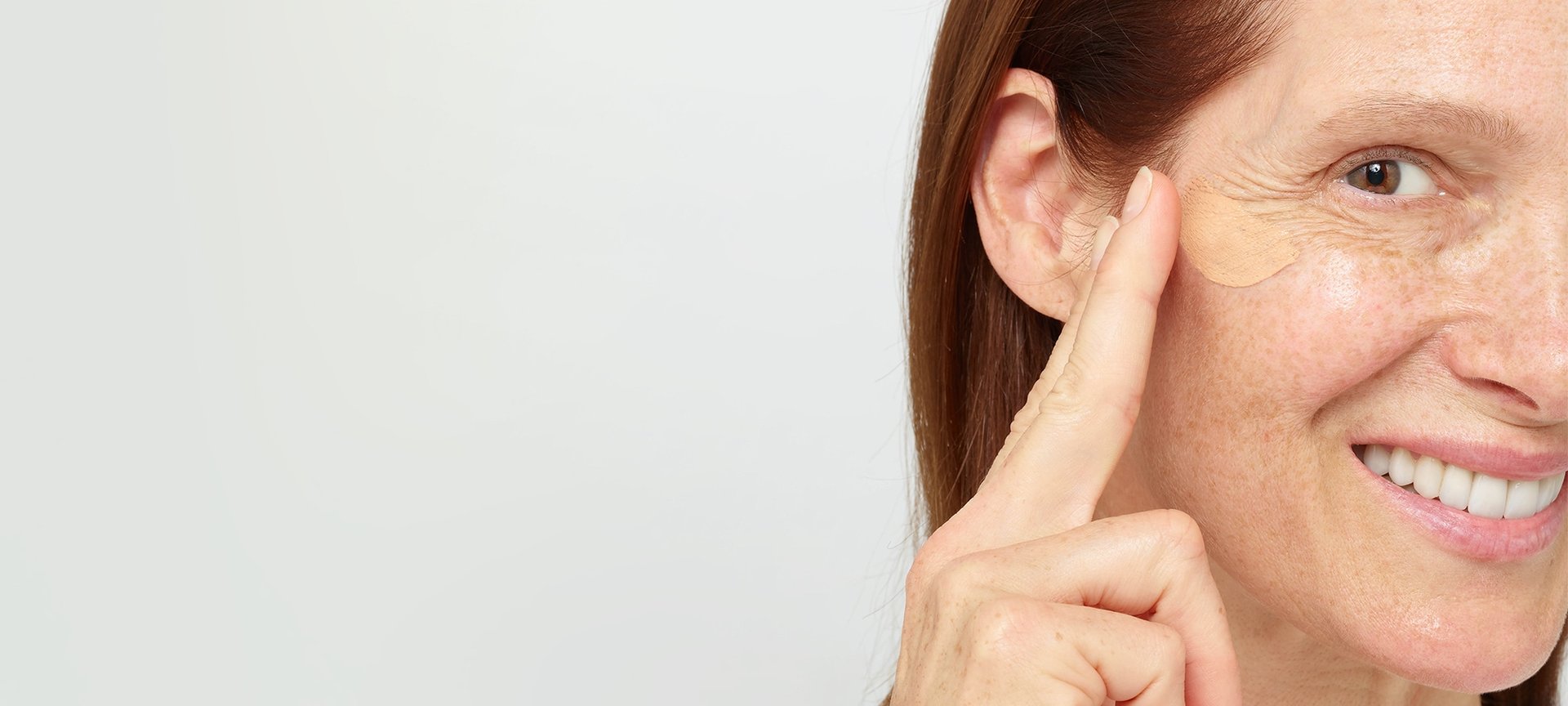 Eine Frau trägt eine Hautcreme auf ihre rechte Wangenpartie auf