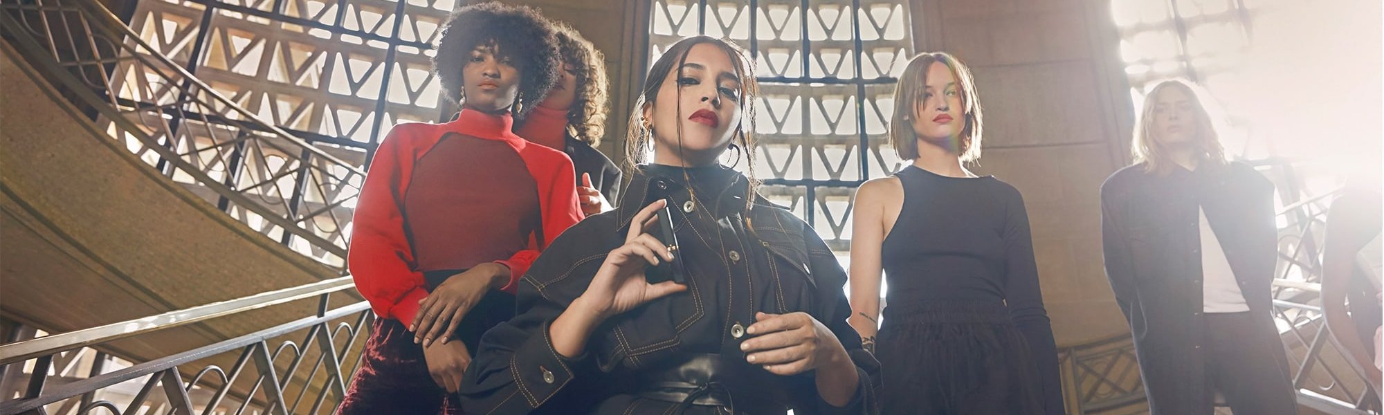 Fuenf Frauen posieren auf einer Treppe mit Lippenstift in einer Hand